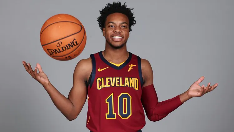 a dark-skinned guy in a basketball uniform throws a basketball